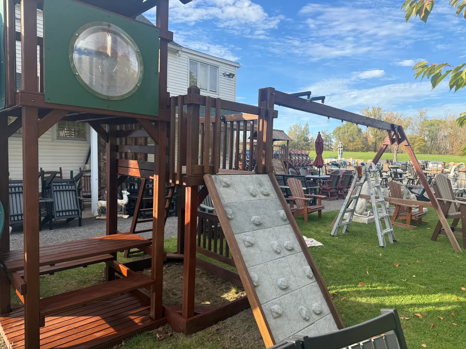 Wooden backyard playset freshly stained a deep red brown with a climbing wall and swing beam