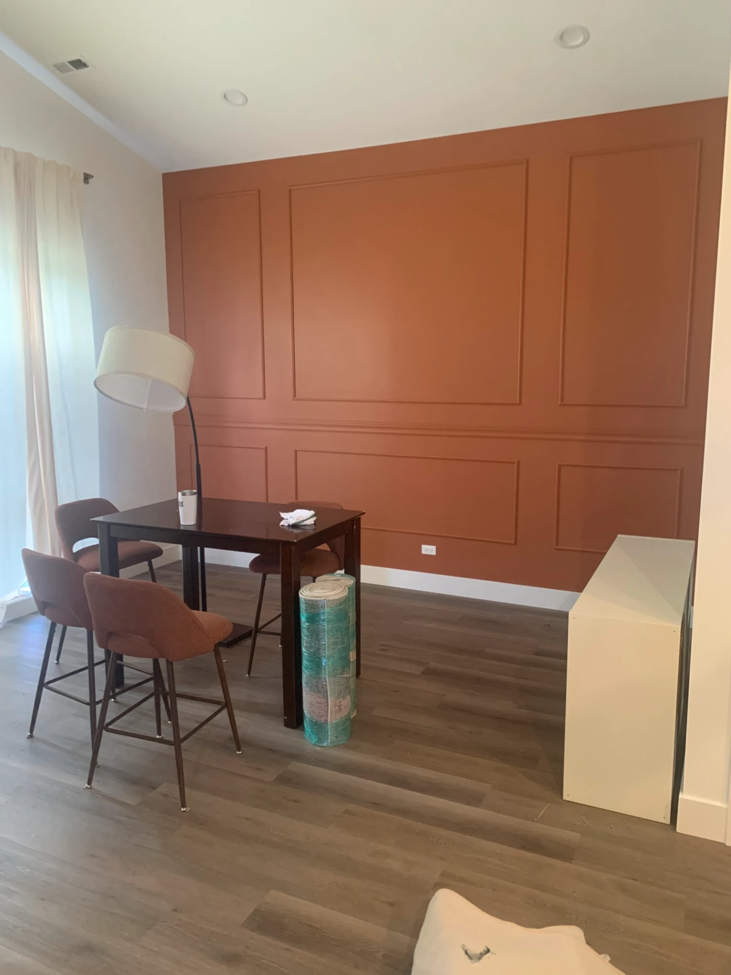 Dining area with a terracotta accent wall and painted picture frame molding